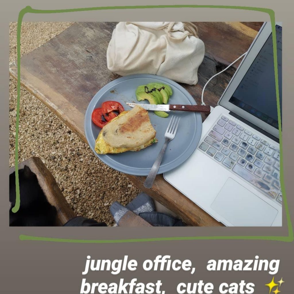 A digital nomad works with her computer and eats brunch at Hydra jungle coworking cafe in Tulum, Mexico